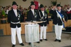 Zwei Kinder in traditioneller Tracht, eines mit Hut und das andere mit Blumenstrauß, stehen nebeneinander.
