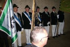 Schwarz-weißes Gruppenfoto von Männern in Anzügen und Hüten, die eine Fahne halten.