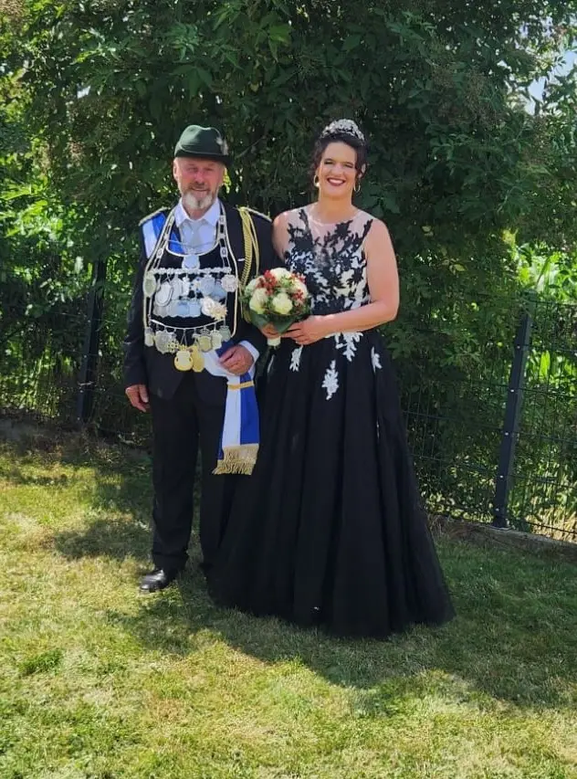 Gerd Josek und Tina Vorsthove stehen im Freien; er trägt eine Schützenkette, sie ein schwarzes Kleid mit Blumenstrauß.